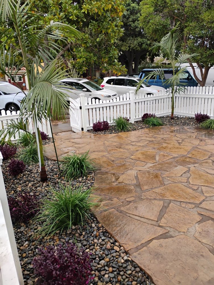 Flagstone patio with palm trees and river rock landscaping by A.G Landscape